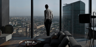 Pessoa observando a cidade de uma janela panorâmica em um studio moderno, representando o conceito de hybrid living urbano com conforto e praticidade.