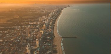 Vista aérea de Balneário Piçarras ao entardecer, mostrando o encontro entre o mar e a cidade, cenário que inspira o conceito do empreendimento Naut.